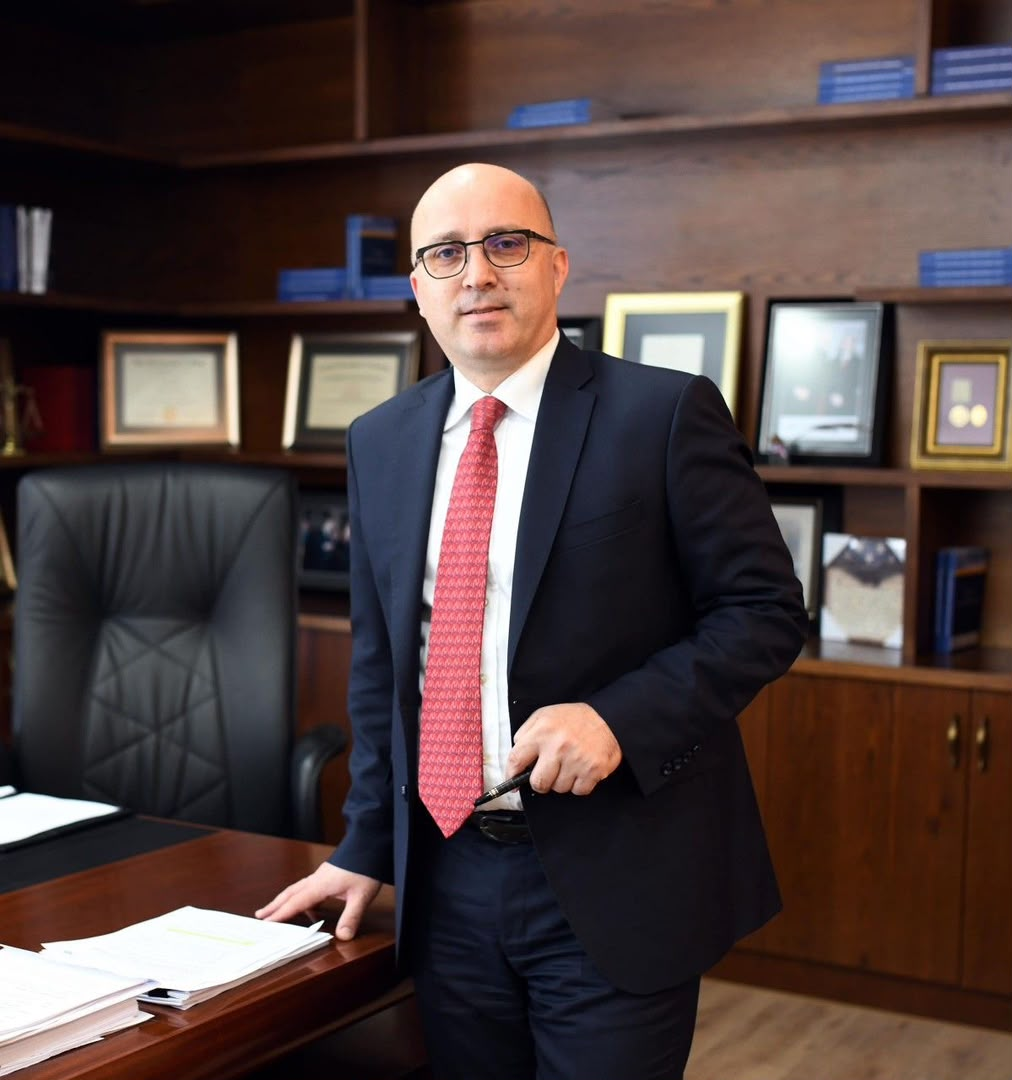 Professional in a dark suit standing at a desk in an office